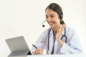 médico ou médico vestindo branco casaco, estetoscópio usando fone de ouvido, consultando saúde de telessaúde conectados para Falando vídeo ligar consulta em tábua. telemedicina de médico para distância paciente. foto