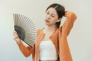 sofrimento verão calor AVC, quente clima, cansado ásia jovem mulher, menina suado e sedento, refrescante com mão dentro sopro, onda ventilador para ventilação quando temperatura Alto às lar, casa.em fundo foto