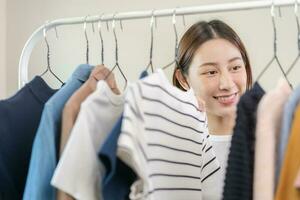 escolha do roupas, nada para vestir. atraente ásia jovem mulher, menina experimentar em aparecer, feliz escolhendo vestir, equipamento em cabide dentro guarda roupa dentro quarto armário de roupa às lar. decidir blusa o que para colocar em que 1 foto