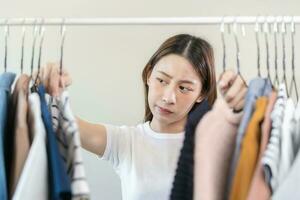 escolha do roupas, nada para vestir. atraente ásia jovem mulher, menina experimentar em aparecer, feliz escolhendo vestir, equipamento em cabide dentro guarda roupa dentro quarto armário de roupa às lar. decidir blusa o que para colocar em que 1 foto