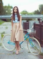 jovem bonita e elegantemente vestida com bicicleta foto