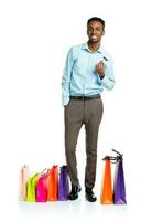 feliz africano americano homem com compras bolsas e segurando crédito cartão em branco fundo foto