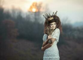 jovem menina dentro uma branco renda vestir, uma coroa do galhos com uma ramalhete do seco flores foto