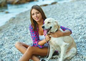 mulher com uma cachorro em uma andar em a de praia foto