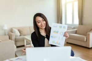 empresária apresentando gráficos e gráficos em vídeo ligar on-line. meia idade o negócio mulher tendo conferência ligar com cliente em computador portátil. fechar-se o negócio mulher trabalhando computador portátil computador interior. foto