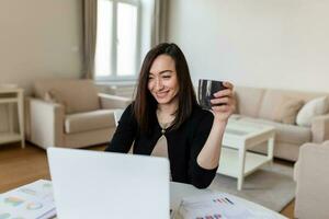 ásia mulher trabalhando em computador portátil computador, sorridente. mulher trabalhando a partir de casa em computador portátil dentro moderno apartamento. na moda mulher trabalhando em computador portátil a partir de casa foto