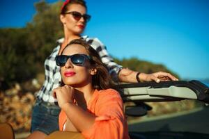 dois jovem feliz meninas tendo Diversão dentro a cabriolet ao ar livre foto