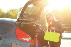 mulher colocando dela compras bolsas para dentro a carro tronco foto