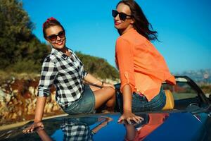 dois jovem feliz meninas tendo Diversão dentro a cabriolet ao ar livre foto