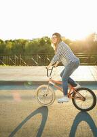 adorável jovem mulher dentro uma chapéu equitação uma bicicleta em cidade fundo dentro a luz solar ao ar livre foto