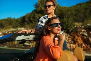 dois jovem meninas tendo Diversão dentro a cabriolet ao ar livre foto