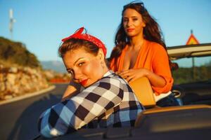dois jovem feliz meninas tendo Diversão dentro a cabriolet ao ar livre foto