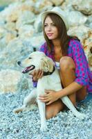 mulher com uma cachorro em uma andar em a de praia foto