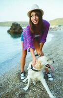 mulher com uma cachorro em uma andar em a de praia foto