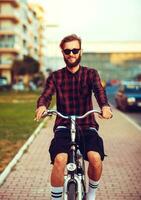 à moda homem dentro oculos de sol equitação uma bicicleta em cidade rua foto