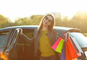 sorridente caucasiano mulher colocando dela compras bolsas para dentro a carro foto