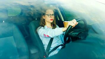 jovem mulher com café para ir dirigindo dela carro foto