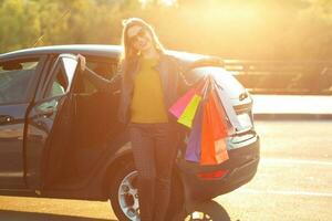 sorridente caucasiano mulher colocando dela compras bolsas para dentro a carro foto