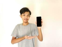 ásia jovem homem mostrando Smartphone com em branco tela foto