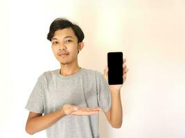 ásia jovem homem mostrando Smartphone com em branco tela foto