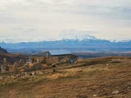 a velho pedra convidado casa Alto dentro a montanhas contra a pano de fundo do Nevado majestoso picos. difícil natural condições do vivo dentro a montanhas, pobre vida. foto