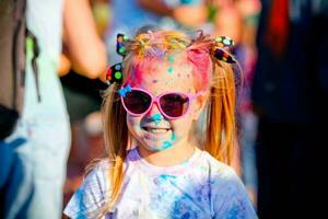 criança dentro verde cores holi. holi facial tiro em Primavera cor festival do holi. holi celebração conceito. a retrato risos a menina dentro a oculos de sol às pintura festa foto