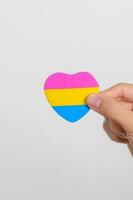 pansexual orgulho dia e lgbt orgulho mês conceito. mão segurando rosa, amarelo e azul coração forma para lésbica, gay, bissexual, transgênero, queer e pansexual comunidade foto