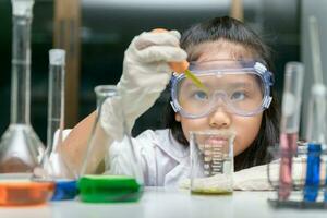 pequeno menina vestindo seguro óculos de proteção fazer experimentar foto