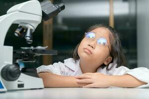 pequeno criança pensando e Aprendendo dentro escola laboratório foto