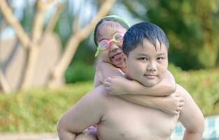 irmão segurando dele irmã em dele costas dentro natação piscina, foto
