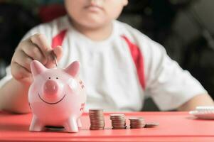 mão Garoto colocar moeda para porquinho banco, salvando dinheiro foto