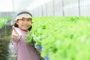 fofa menina mostrando polegar acima às orgânico vegetal Fazenda foto