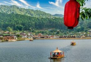 lanternas chinesas e barcos no lago com pôr do sol sobre ban rak thai foto