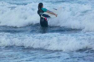 surfistas obtendo pronto para entrar a água e caminhando com a borda ao longo a costa. foto