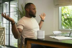 estressante africano americano homem trabalhando dentro dele casa foto