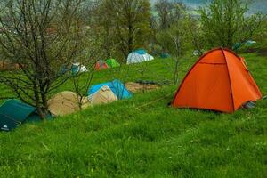 acampamento tendas em uma verde Prado dentro a montanhas dentro Primavera. descansar com a barraca dentro natureza foto