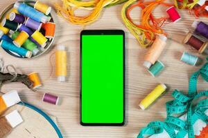 Smartphone com uma verde tela, croma chave brincar para a aplicativo. conceito do bordado, de costura ou bordado com tópicos. fundo com colori tópicos. foto