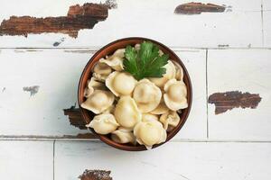 pelmeni tradicional, ravioli, bolinhos recheados com carne no prato, cozinha russa. fundo rústico de madeira, copie o espaço. foto