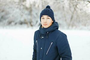 jovem homem dentro à moda inverno roupas em uma fundo do Nevado parque foto