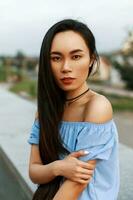 lindo jovem vietnamita menina com grandes Penteado dentro uma azul blusa com nu ombros em uma verão dia foto