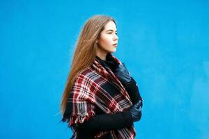 fêmea perfil. lindo jovem menina com uma cachecol e casaco perto a azul parede foto