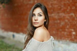 lindo retrato do uma jovem bonita mulher com cabelo dentro uma cinzento vintage suéter em uma vermelho fundo foto