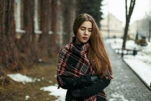 lindo à moda menina com uma à moda cachecol dentro uma Nevado dia foto