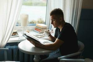 bonito homem com café lendo uma livro. foto