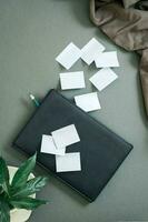 verde conceito. bloco de anotações, folhas para escrevendo e fresco folhas dentro uma café copo em uma verde fundo. topo e vertical Visão foto