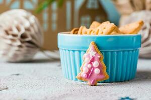 Natal biscoitos abeto com Rosa gelo estão colocada perto uma tigela do biscoitos em uma decorado mesa. festivo tratar. fechar-se foto