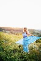 menina loira com cabelo solto em um vestido azul claro e um cara na luz do pôr do sol foto