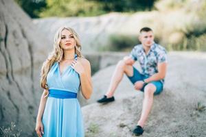 garota loira com um vestido azul claro e um cara com um short claro em uma pedreira de granito foto