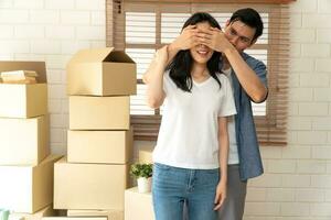 sorridente jovem ásia feliz casal fechar namorada olhos para uma surpresa às comovente dia dentro seus Novo casa depois de comprando real Estado. conceito do iniciando uma Novo vida para uma recentemente casado casal. foto