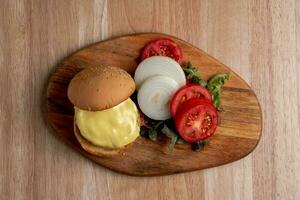 topo Visão do fresco saboroso caseiro Hamburger com fresco vegetais, alface, tomate, queijo ao lado fatiado tomates em uma corte borda. livre espaço para texto foto